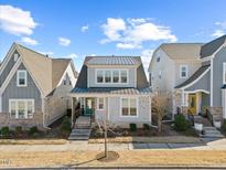 Charming two-story home featuring a metal roof, beautiful light-gray siding, and a welcoming, teal-painted front door at 5520 Advancing Ave, Raleigh, NC 27616