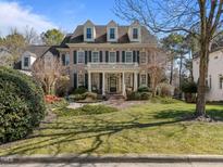 Charming brick home boasts a manicured lawn, mature landscaping, and a welcoming front porch with classic columns at 12344 Canolder St, Raleigh, NC 27614