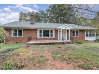 Charming brick home featuring a covered front porch, mature trees, and a cozy, inviting appeal at 1807 S Mebane St, Burlington, NC 27215