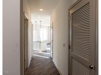 Bright hallway featuring wood floors leads to a modern kitchen with stainless steel appliances at 2300 Gathering Sq Ct, Fuquay Varina, NC 27526