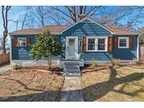 Charming blue home featuring crisp white trim, gray steps and walkway, and decorative brown window shutters at 2407 Cascadilla St, Durham, NC 27704