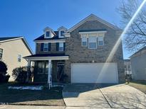 Charming two-story brick home with a two-car garage and well-manicured lawn on a sunny day at 264 Steel Hopper Way, Garner, NC 27529
