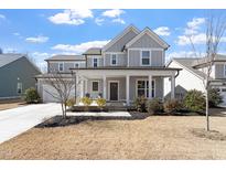 Charming gray two-story home featuring a welcoming front porch and well-manicured landscaping at 3021 Falco Field Ln, Fuquay Varina, NC 27526