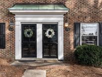 Charming brick home featuring dual front doors with wreaths and black shutters at 3721 Browning Pl, Raleigh, NC 27609