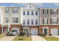 Inviting townhome showcasing brick accents, white siding, a single-car garage and manicured landscaping at 405 Coral Creek Ln, Morrisville, NC 27560