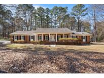 Charming brick home with black shutters and a covered front porch, set amidst mature trees at 4913 Stillmeadow Rd, Raleigh, NC 27604