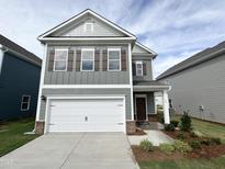 Charming two-story home with a white garage door, gray siding, and a well-maintained front yard at 52 Commons Cir, Clayton, NC 27520