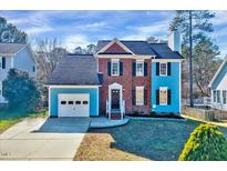 Charming two-story home featuring a brick facade and blue siding, with a well-maintained lawn and attached garage at 5904 Eaglesfield Dr, Raleigh, NC 27613