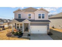 Charming two-story home with gray siding, a covered porch, and an attached two-car garage at 6902 Bedrock Rd, Mebane, NC 27302
