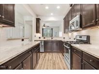 Galley kitchen features granite counters, stainless appliances and dark wood cabinets, with a peek to the breakfast area at 736 Wickham Ridge Rd, Apex, NC 27539