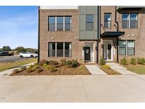 Inviting brick townhome featuring well-manicured landscaping and sidewalk leading to the front door at 1259 Shaw View Alley # 101, Raleigh, NC 27601