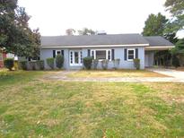 Charming single-story home with grey brick, manicured bushes, and a covered driveway at 136 Dogwood Trl, Wendell, NC 27591