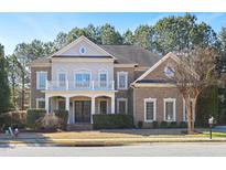 Elegant brick home with a charming front porch, second story balcony, and manicured landscaping at 2012 Wide River Dr, Raleigh, NC 27614