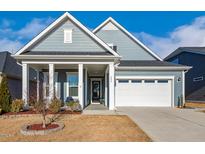 Charming blue home featuring a well-manicured lawn, inviting front porch, and a two-car garage at 244 Bevis Marks Dr, Fuquay Varina, NC 27526