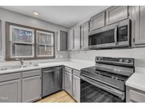 Well-lit kitchen featuring modern appliances, gray cabinets and light countertops at 6036 Epping Forest Dr, Raleigh, NC 27613