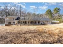 An exterior rear view of a house featuring an enclosed porch and a spacious backyard at 10611 Quail Roost Rd, Bahama, NC 27503