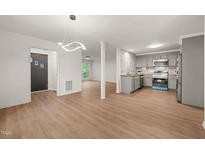 Open concept living room and kitchen area with hardwood floors and modern lighting fixture at 1411 Rosewood St, Durham, NC 27701