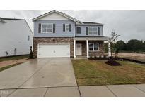 Charming two-story home with a stone facade, blue siding, manicured lawn, and a two-car garage at 149 Ethel Ln, Angier, NC 27501