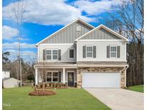 Charming two-story home with a stone-accented garage and covered porch, set against a blue sky at 219 E American Merigold Dr # 45, Benson, NC 27504