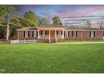 Charming red brick home featuring a welcoming front porch and a well-manicured lawn at 41 E T Hanner Rd, Bear Creek, NC 27207