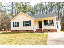 Charming yellow home featuring blue shutters, a brick foundation and a front yard at 5748 Presentation St, Knightdale, NC 27545