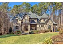 A beautiful stone home with a manicured lawn and mature trees offers luxury living at 6105 Valencia Ct, Raleigh, NC 27614