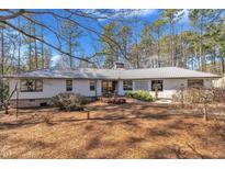 Charming single-story home features a metal roof, inviting facade, and a lush yard with mature landscaping at 723 Chelsea Dr, Sanford, NC 27332
