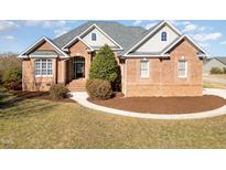 Charming brick home featuring a landscaped front yard, arched entryway, and multiple windows at 7800 Twin Pines Way, Fuquay Varina, NC 27526
