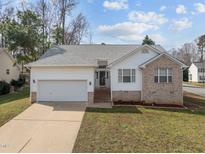 Charming home with a two-car garage, manicured lawn, brick accents, and mature trees offering curb appeal at 100 W Acres Cres, Cary, NC 27519