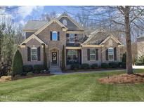 Beautiful two-story home with brick and stone exterior, well-manicured lawn and mature landscaping at 106 Rolling Meadows Ln, Chapel Hill, NC 27517