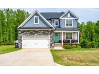 Charming two-story home showcasing a stone facade, attached garage, and inviting front porch with a vibrant turquoise door at 201 Northview Dr, Middlesex, NC 27557