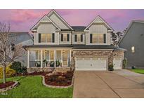 Charming two-story home featuring a stone facade, inviting front porch, and well-manicured lawn with flowering trees at 3460 Willow Green Dr, Apex, NC 27502