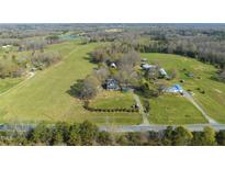 Expansive aerial view of a farmhouse estate with fields, trees, and outbuildings at 7055 Old 421 Rd, Liberty, NC 27298