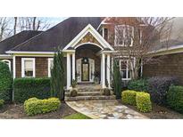Inviting home exterior with a stone archway, well-manicured landscaping, and a flagstone walkway at 1004 Colworth Way, Raleigh, NC 27614