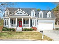 Charming two-story home with a welcoming front porch, red door and well-manicured lawn at 105 Talisker Ct, Apex, NC 27502