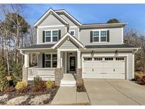 Charming two-story home featuring a covered porch, two-car garage, and a beautifully landscaped front yard at 120 Breyla Way, Holly Springs, NC 27540