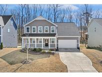 Charming two-story home with a welcoming front porch and a well-manicured lawn, complete with an attached two-car garage at 143 Rossell Park Cir, Garner, NC 27529
