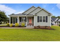 Charming home featuring a covered porch, well-maintained lawn, and a delightful peach-colored front door at 23 Sparkle Ln, Garner, NC 27529