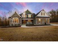 Charming two-story home boasting a stone facade, inviting front porch, and manicured lawn in a serene setting at 1636 Sweetwater Ln, Raleigh, NC 27610