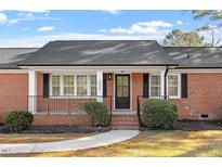 Charming brick home featuring a covered front porch, black shutters and lush landscaping at 200 Arlington Cir Cir, Sanford, NC 27330