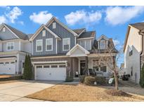 Charming two-story home with blue siding, brick accents, a front porch, and a two-car garage at 2005 Cotton Barn Ct, Wendell, NC 27591