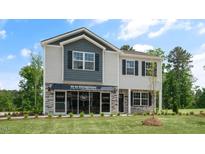Inviting two-story home featuring stone accents, covered entrance, lush lawn, and professionally landscaped grounds at 2006 Fletcher'S Ridge Dr, Durham, NC 27703