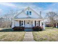 Charming two-story home featuring a quaint front porch, brick chimney and landscaped front yard at 204 N Sixth St, Mebane, NC 27302