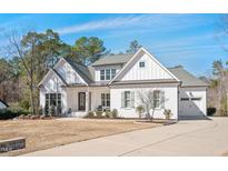 Inviting white brick home featuring a manicured lawn and mature trees at 2412 Toll Mill Ct, Raleigh, NC 27606