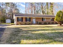 Charming ranch-style home with brick facade, manicured front yard, and a detached storage shed at 2606 Landis Dr, Durham, NC 27705
