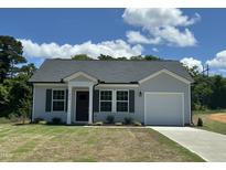 Charming single-Gathering home featuring gray siding, a black roof, a well-manicured lawn, and an attached garage at 272 Johnson Ridge Way, Four Oaks, NC 27524