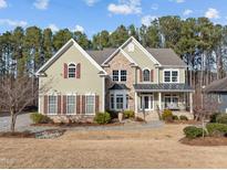 Charming two-story home featuring a stone facade, manicured lawn, and inviting front porch at 47 Dover Grant Ct, Chapel Hill, NC 27517