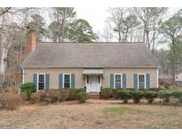 Charming single-story home with a brick chimney and landscaped front yard with inviting blue shutters at 115 Perth Pl, Durham, NC 27712