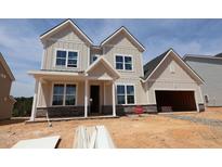 New two-story home with a two-car garage, covered front porch, and stone accents, situated on a lot under construction at 1204 Opal Ln # 93, Durham, NC 27705