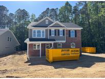 Two-story home with gray siding, brick accents, black shutters, and visible dumpster at 1849 Ballard Rd # Holly Georgian, Fuquay Varina, NC 27526
